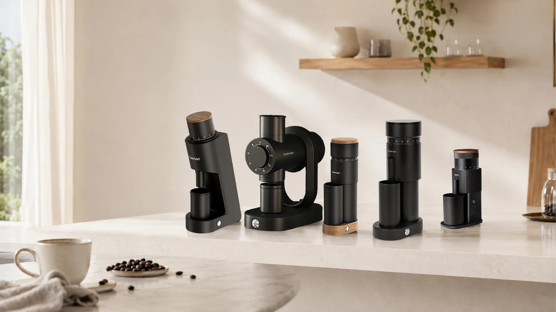 A set of modern black coffee brewing and grinding devices arranged on a light countertop in a bright, minimalist kitchen setting with a coffee cup and beans nearby.slider_item_hXciyi