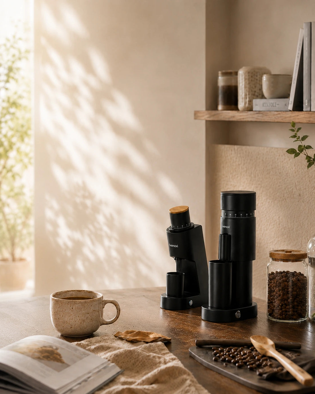 Geimori GU63 and GU38 on a wooden table in a warm, sunlit kitchen or cafe setting, with a coffee cup, open book, jars of coffee beans, and a chair in the background.slider_item_3FJgtJ